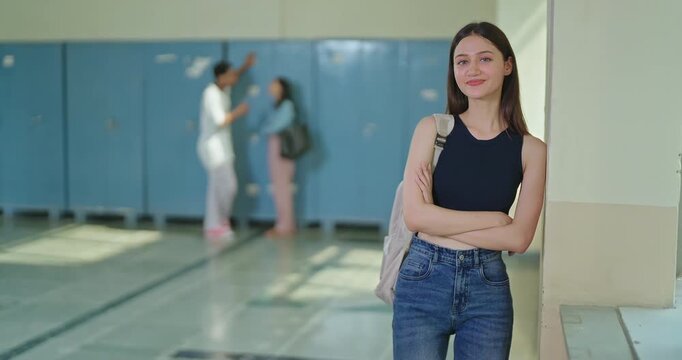 Indian young adult gen z proud lady female look camera cross arm standing campus area. smart teen pupil girl wear bag fold hand staring cam do casual pose enjoy new day time inside college place