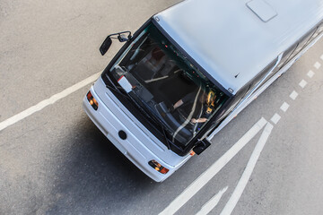 Tour bus moves along city street top view