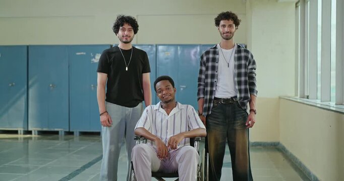 Indian young adult smart proud man guys group look camera fold hand place gen z boy male pupil sitting wheel chair team mate staring cam cross arms do casual pose ready for exam enjoy new course day	