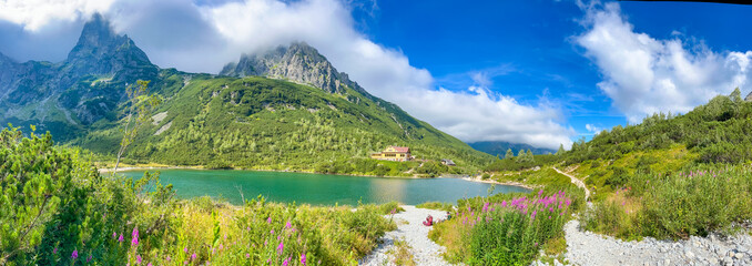 Scenic panoramic view of alpine mountain valley with green slopes and clear sky. Concept: wilderness, outdoor exploration, adventure.