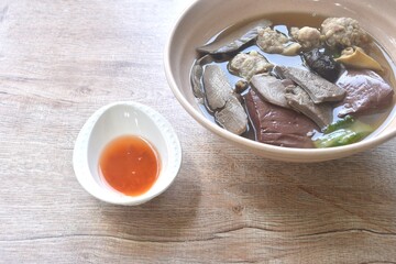 boiled pork blood and entrails with chop pork topping black mushroom in soup on bowl dipping spicy sour chili sauce 