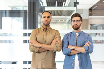 Confident business professionals posing in modern office environment with crossed arms