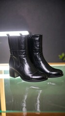 Pair of black leather ankle boots on a glass display