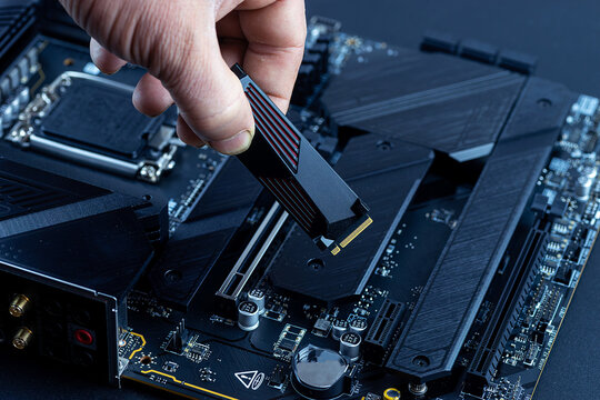 Personal computer technicians mounting ssd drive on the motherboard socket, pc assembling.