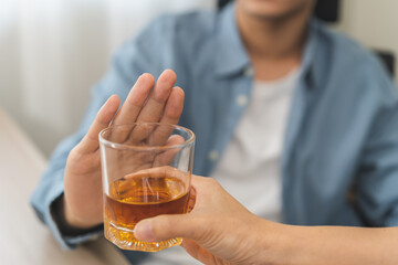 Alcoholism, depressed asian young man refuse, push out alcoholic beverage glass, drink whiskey,...