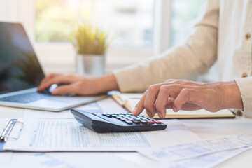 Account finance, asian young business man hand using calculator, laptop computer for calculate budget, cost and income of company from paperwork, plan spend money expenses, working on desk at home.
