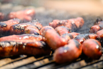 Chorizo sausages cooking on a smoky barbecue grill, a summer barbecue feast.