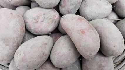 close up of a pile of muddy red skinned potatoes on a dark earthy background