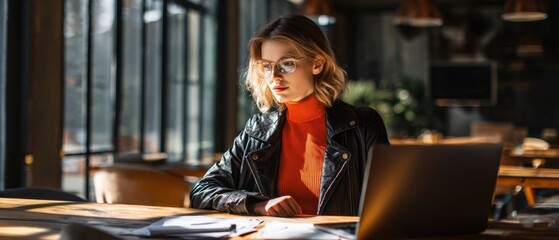 The focused woman working on her laptop in a stylish coffee shop environment.