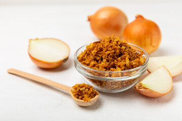 Crispy fried onions in a bowl on a wooden table. Roasted Onions. Seasoning for dishes. Spices....