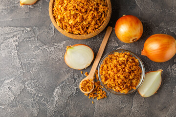 Crispy fried onions in a bowl on a wooden table. Roasted Onions. Seasoning for dishes. Spices....