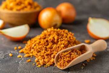 Crispy fried onions in a bowl on a wooden table. Roasted Onions. Seasoning for dishes. Spices....