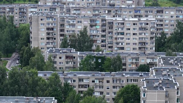 Close-up view of Soviet-era apartment blocks in Vilnius, Lithuania, with repetitive architecture, balconies, and greenery surrounding the buildings.