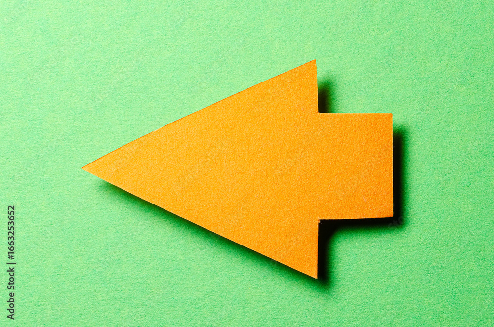 Poster orange cut out blank paper cardboard arrow direction sign with copy space for text on green backgrou