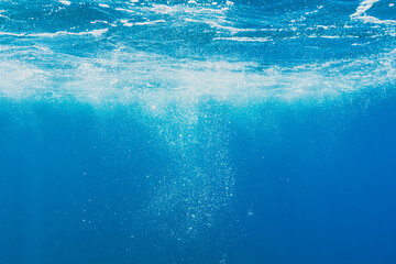 An abstract underwater background of the deep blue ocean with sparkling air bubbles rising up to...