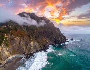 Rugged coastal cliffs with turquoise ocean at sunrise - aerial panoramic seascape with light mist,...