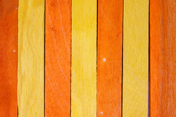 Vertical arrangement of alternating yellow and orange wooden planks, close-up abstract texture...