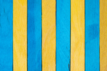 Vertical alignment of alternating blue and yellow wooden sticks, creating a structured, rhythmic...