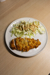 A plate of pork tonkatsu with cabbage salad.