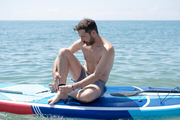 Stand up paddle surfer preparing on board in the sea