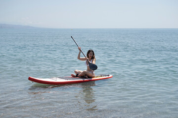 Young woman paddling on sup board in calm sea