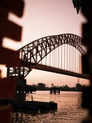 A bridge standing over a river and the morning atmosphere with the sunlight starting brighten the sky
