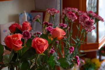 Beautiful bouquet of vibrant roses and carnations in a cozy indoor setting with soft natural light.