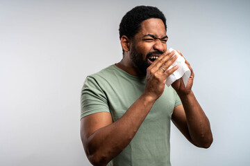 Man blowing nose, isolated background, suffering from cold or allergy, sick adult male indoors,...
