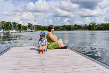 Mum and son enjoying a sunny day by the water on a wooden dock