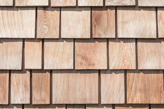Wooden shingle roof background of new red brown cedar shake wood tile siding row panel pattern made of larch conifer tree in building construction for house design industry