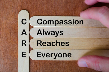 Wooden stick acronym CARE emphasizing compassion, empathy, inclusion, diversity, kindness, and...