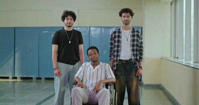 Indian young adult smart proud man guys group look camera fold hand place gen z boy male pupil sitting wheel chair team mate staring cam cross arms do casual pose ready for exam enjoy new course day