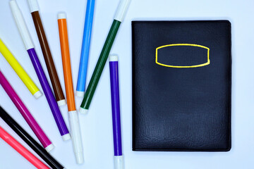Notebook with colorful markers on white background | Buku catatan dengan spidol warna-warni di atas latar putih