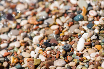 Sea colored pebbles on the beach, clear sea water