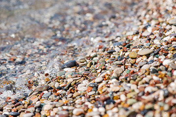 Sea colored pebbles on the beach, clear sea water