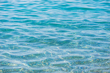 Azure water texture, transparent sea surface with a rocky bottom. Aerial view, natural blue background