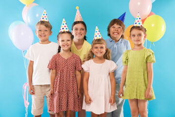 Birthday celebration. Happy kids in party hats and balloons on light blue background
