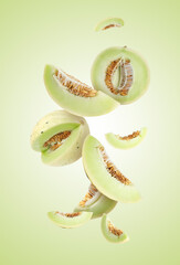 Cut fresh ripe melons swirling in air against light green gradient background