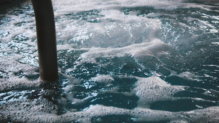 A hydrotherapy pool or hot tub with bubbling water. Part of a ladder is shown. Bubbling and motion...