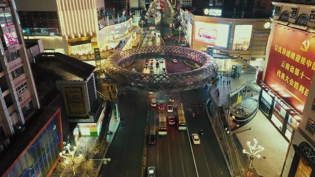 Aerial view of bustling cityscape at night, showcasing a multilevel urban environment with a mix of modern and traditional architecture. The cityscape is illuminated by artificial lights.