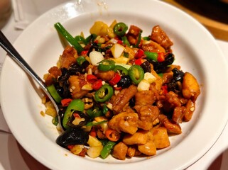 Kung pao chicken stir fry with peppers and peanuts in a white bowl