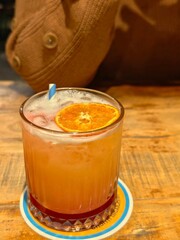 Refreshing orange cocktail with striped straw on wooden table for a vibrant summer drink