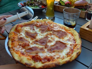 Enjoying a delicious prosciutto pizza with a pizza cutter at a restaurant table
