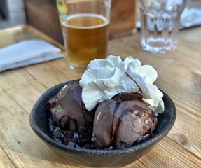 Chocolate ice cream dessert with whipped cream and beer on a wooden table