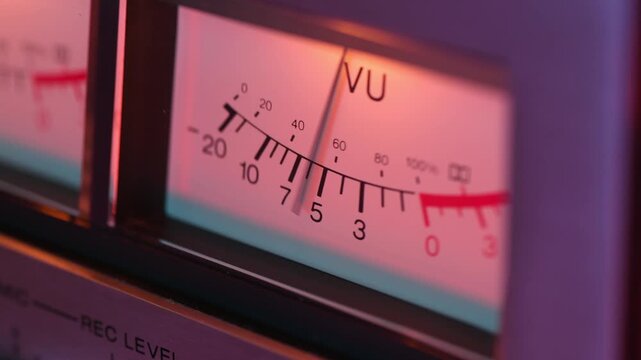 Vintage stereo equipment. Camera pans left to right across illuminated VU meters with a slight tilt, while focus shifts between soft and sharp detail. Needles bounce with sound showing sound levels.