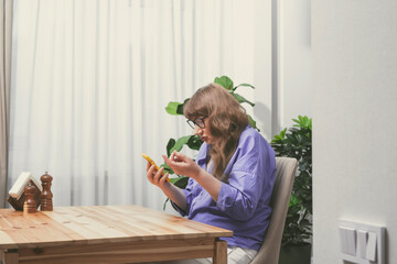 Elderly woman in glasses chatting on smartphone, placing online order or reading social networks...
