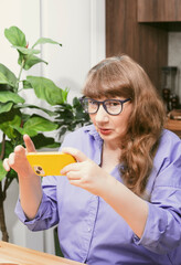 Elderly woman in glasses chatting on smartphone, placing online order or reading social networks...