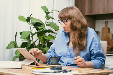Elderly woman professor, teacher, tutor or psychologist reading scientific article on tablet in...