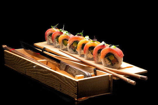 Fresh and delicious sushi rolls with salmon, avocado, and cream cheese on a wooden board. Traditional Japanese food served in a restaurant.