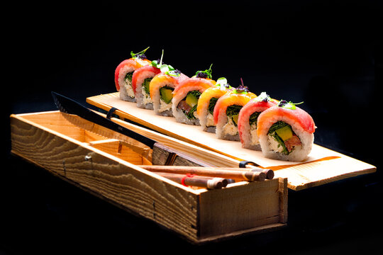 Fresh and delicious sushi rolls with salmon, avocado, and cream cheese on a wooden board. Traditional Japanese food served in a restaurant.